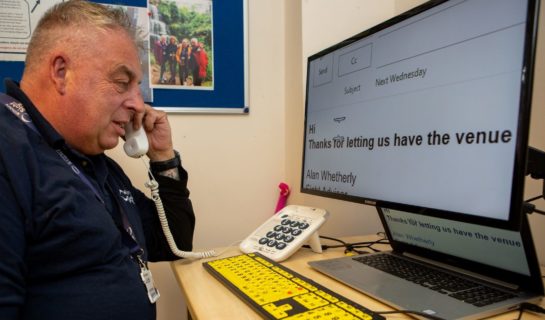 Community Sight Loss Advisor, Alan, sat at his desk taking a call from a client.