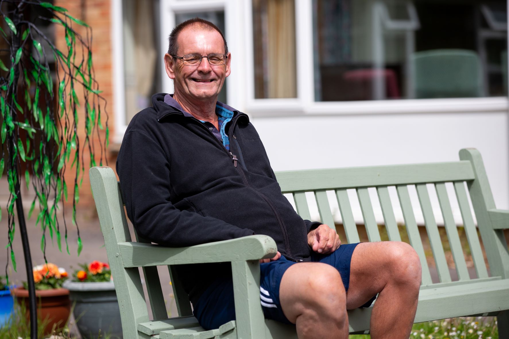 An image of Roberrt, sitting on a bench outside his house.