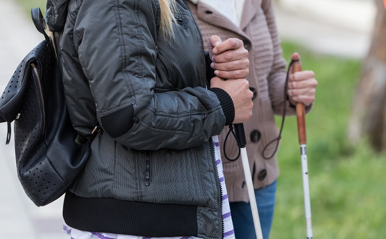 Close up in blind woman's hands holding a cane..