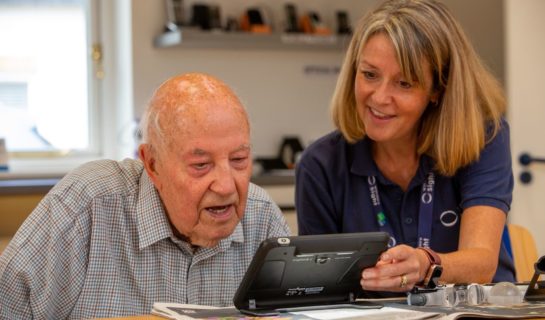 Community sight loss advisor is sitting in the resource centre with a client and they are testing an electronic magnifier.