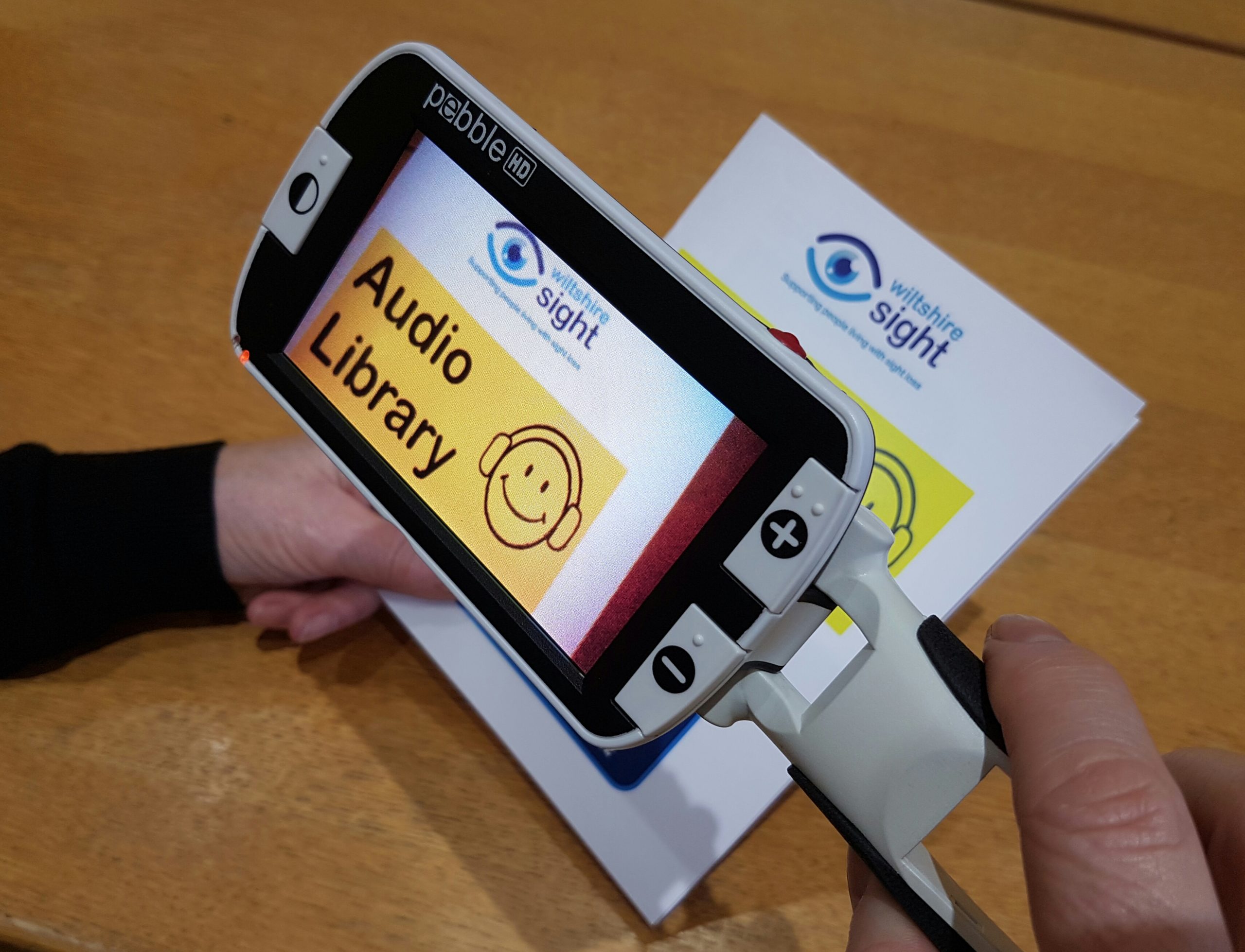 A Pebble hand held magnifier is being held and is magnifying a Wiltshire sight document.