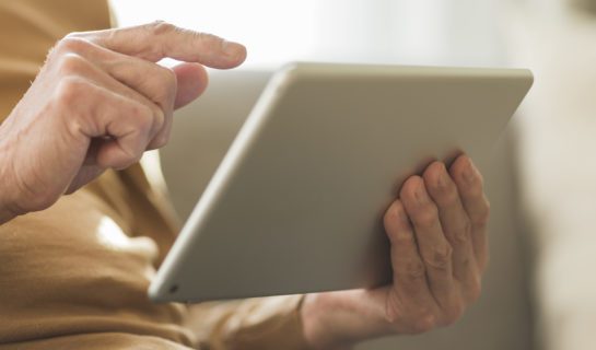 A man is seated using an ipad which has been set up using accessibility settings.