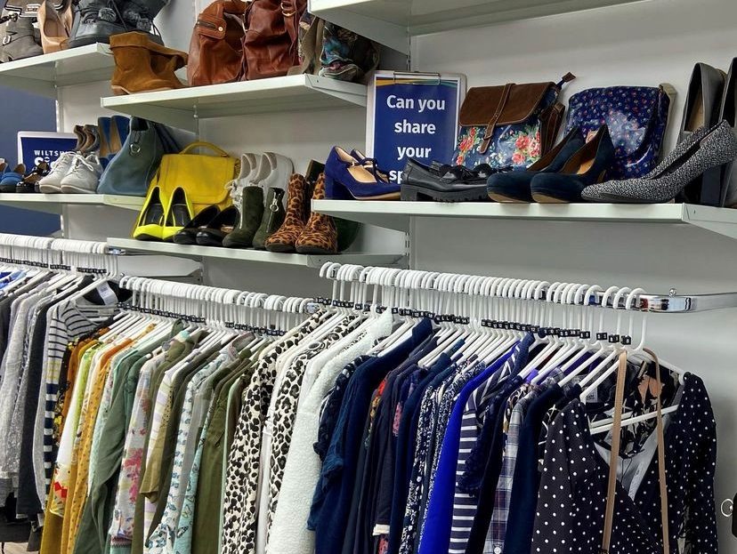 rails of women's tops, shelves above have shoes and bags