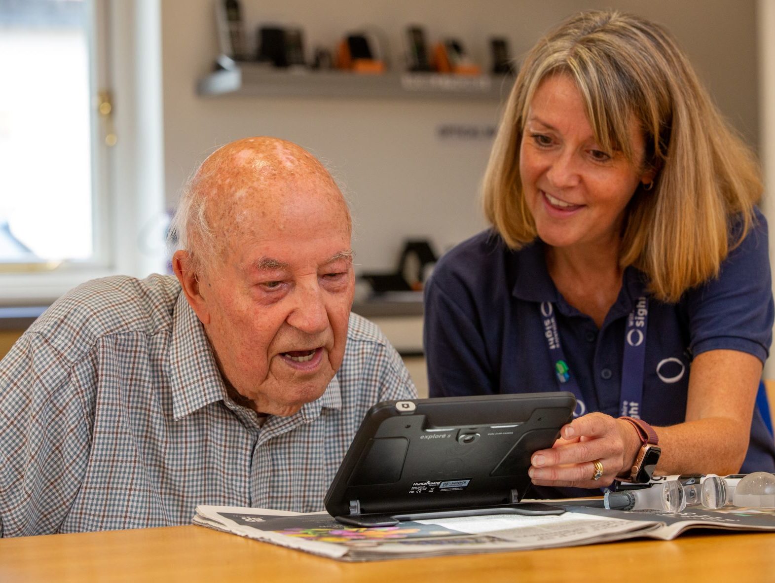 Community sight loss advisor is sitting in the resource centre with a client and they are testing an electronic magnifier.