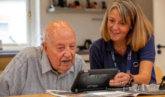 Community sight loss advisor is sitting in the resource centre with a client and they are testing an electronic magnifier.