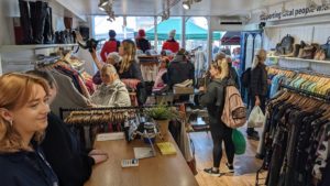 The inside of the shop with our counter and many customers viewing the clothes