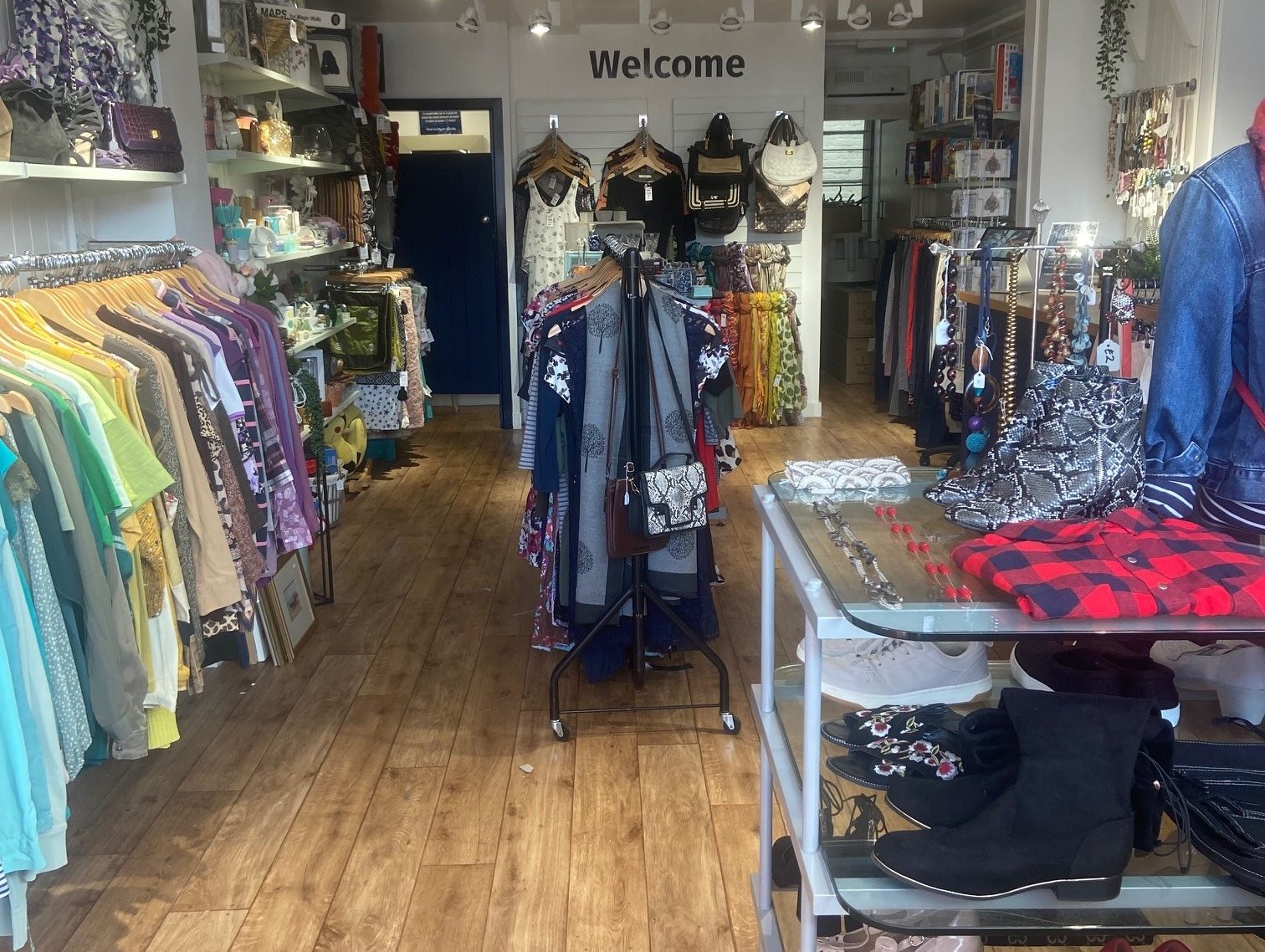 The inside of our shop, clothes are on racks at the side and there is a feature table in the middle of the wooden floor.
