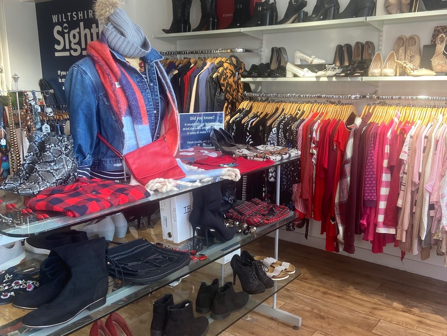 Our shop interior showing the display table and rack of colourful clothing, there are lost of boots and shoes on display too