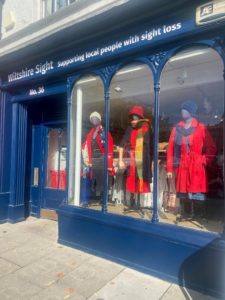 Our shop front, in the 3 panes of glass are 3 mannequins adorned in red clothes. Our wood work is dark blue and Wiltshire Sight is in white writing