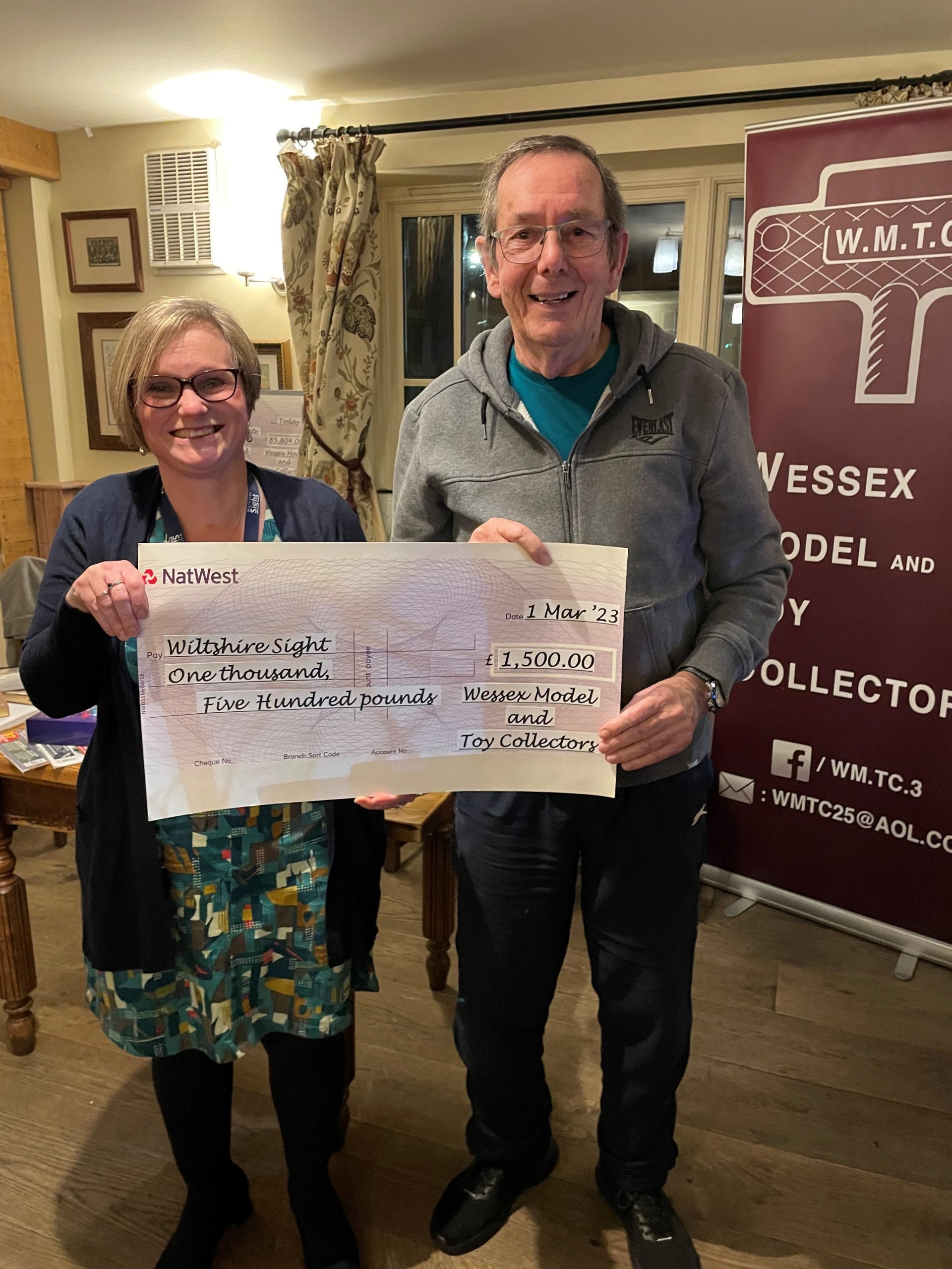 Two people holding a large cheque. Our fundraiser Karen is on the left, with a fundraiser from a group presenting a donation.