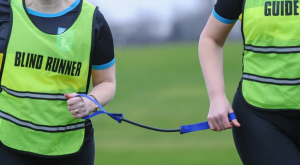 image of a blind runner and sighted guide both holding a piece of cord to eachother.