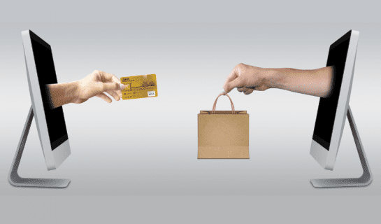 On a grey background two computer screens are facing each other. Two arms extend out from them one holding a paper bag the other some cash.