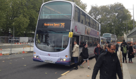 No 75 bus at a stop with people getting on and off