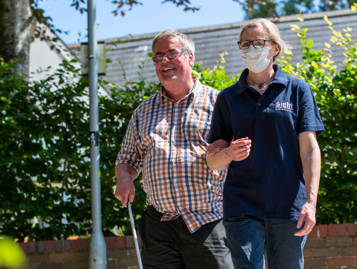 Rehabilitation Officer supporting a gentleman to use his cane independently for an outdoor walk.