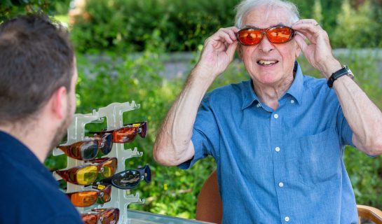 Person trying on eye shields with the help of an Insight Glos Sight Loss Advisor