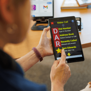 Close up of a person using a tablet with large, high contrast text and icons to make a phone call, showing accessible calling options on the screen.