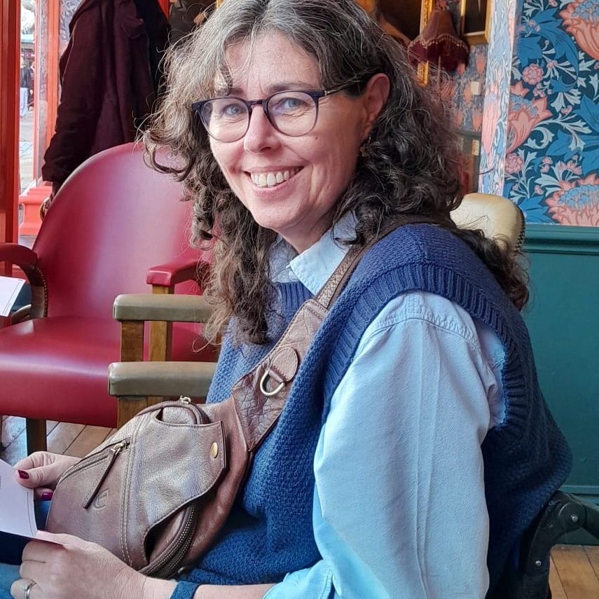 Glenda is wearing a blue top in our charity colours. The photo shows her wheelchair, she is smiling and looking at the camera