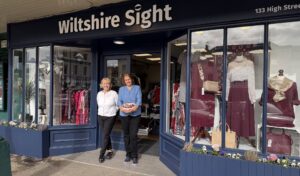 Two members of the Wiltshire Sight team smiling outside the Marlborough charity shop